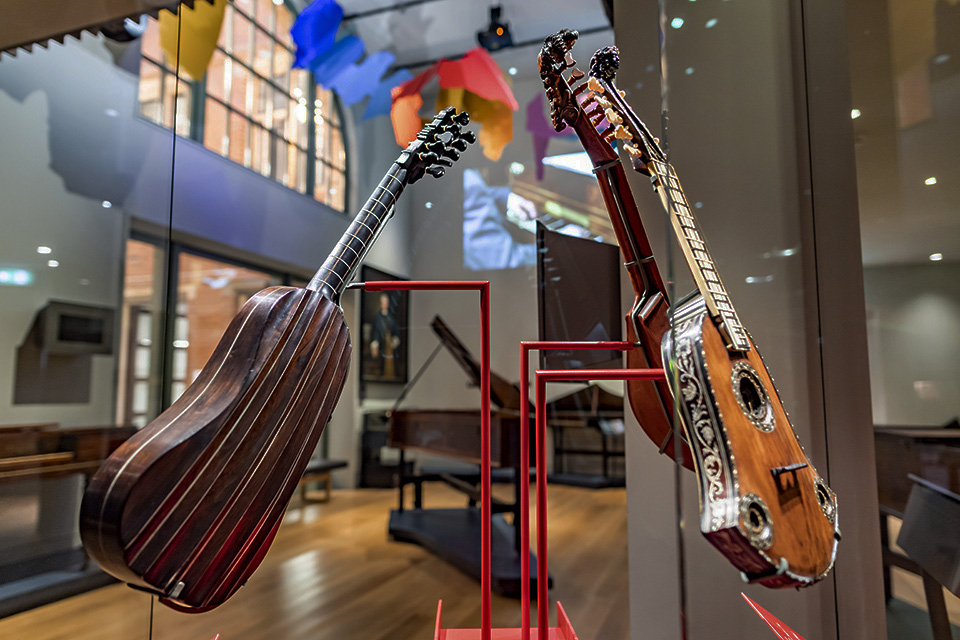 A pair of guitars, intricately designed, sitting in a glass exhibit case in the museum.